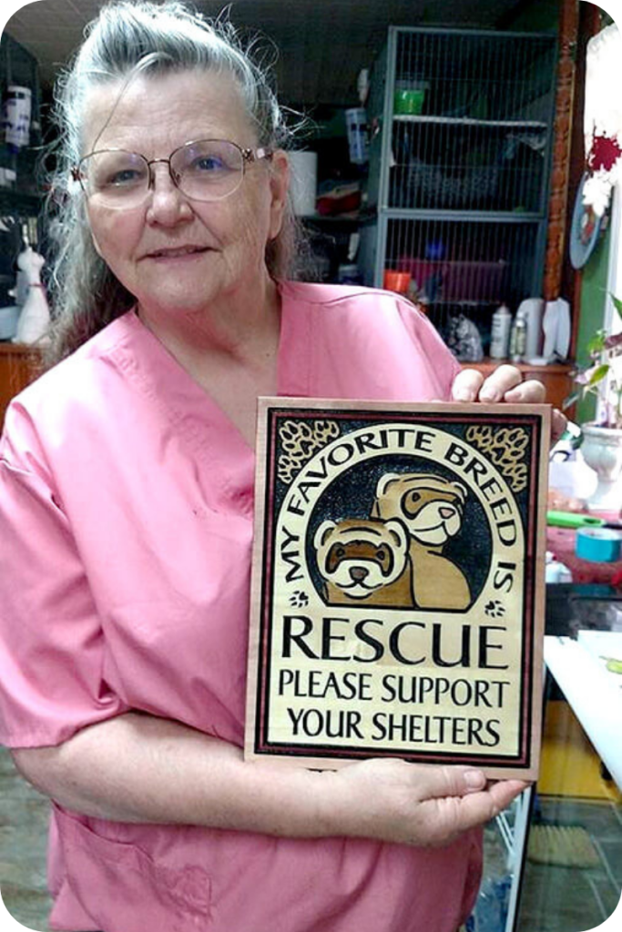 A member of the Texas Ferret Lovers Rescue holds up a sign titled "My Favorite Breed Is Rescue: Please Support Your Shelters"